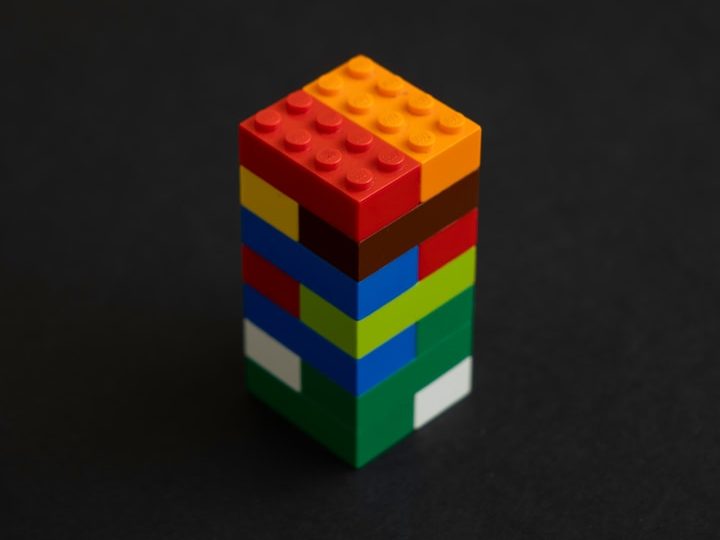 Aufbau Bunte Lego-Steine, vertikal gestapelt, auf schwarzem Hintergrund.